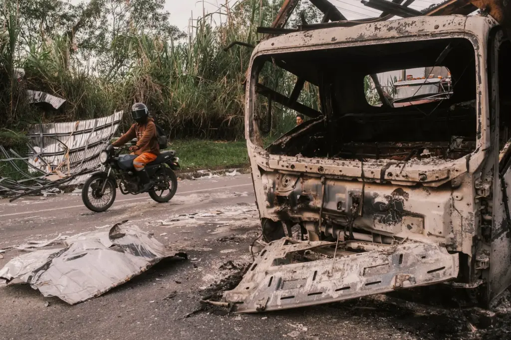 A motorcyclist passes by the remains of a vehicle that was detonated with explosives on the Pan-American highway, in Cauca, on April 29, 2026.