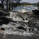 Ash, charred boats, and black water in the San Juan Reservoir after the passage of the flames