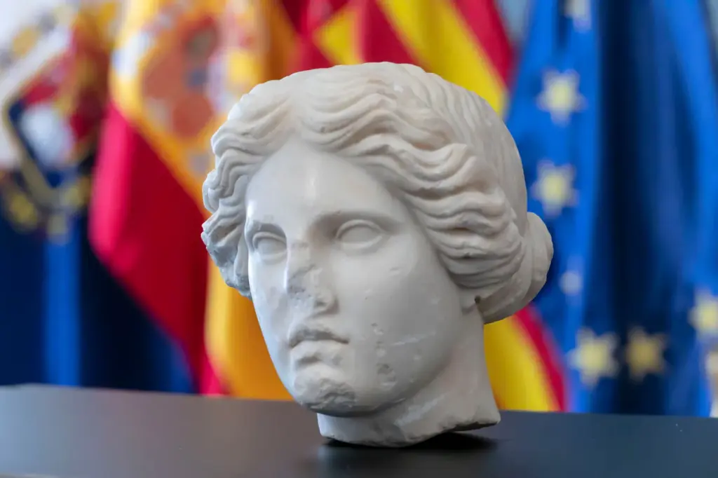 The amazing Venus of Alicante: a 2,000-year-old head peeks out among stones, large beer bottles, and a supermarket bag