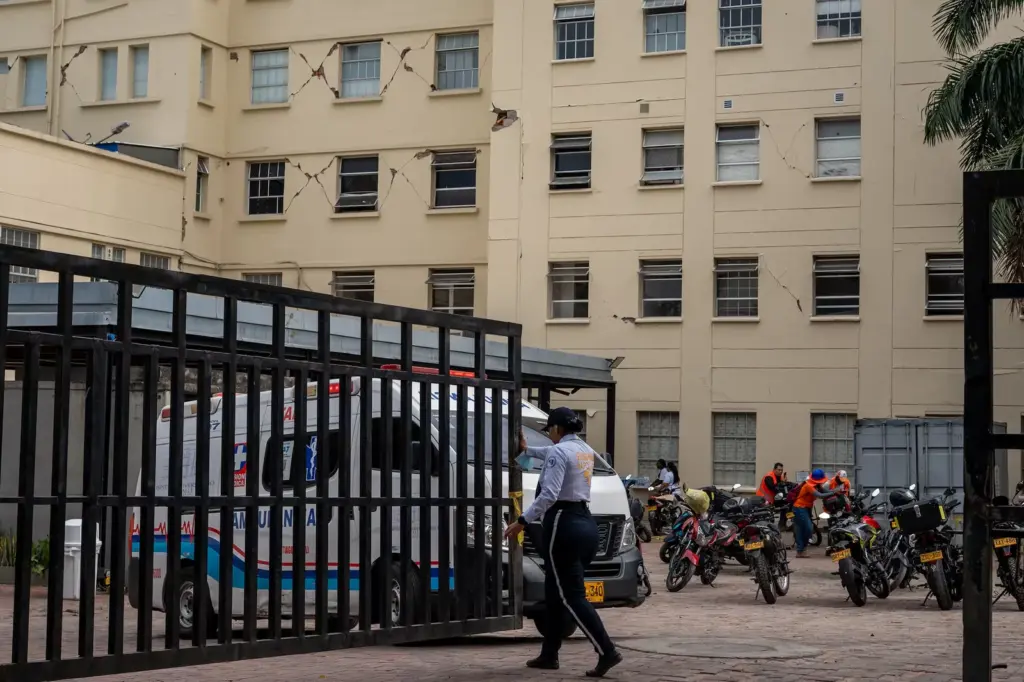A security guard opens the way for an ambulance at the Valle University Hospital (HUV), affected by the earthquake in Colombia, in Cali, on August 14, 2026.