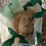 The amazing Venus of Alicante: a 2,000-year-old head peeks out among stones, large beer bottles, and a supermarket bag