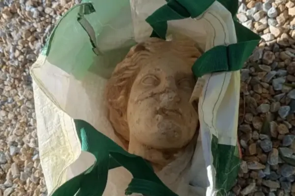 The amazing Venus of Alicante: a 2,000-year-old head peeks out among stones, large beer bottles, and a supermarket bag