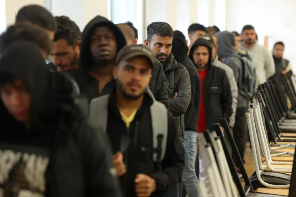 A group of refugees and immigrants line up at a reception center in Eisenhuettenstadt, Germany